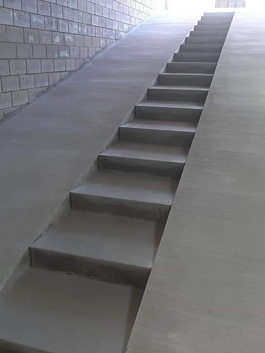Helling in geborstelde beton met trap Rechte trappen